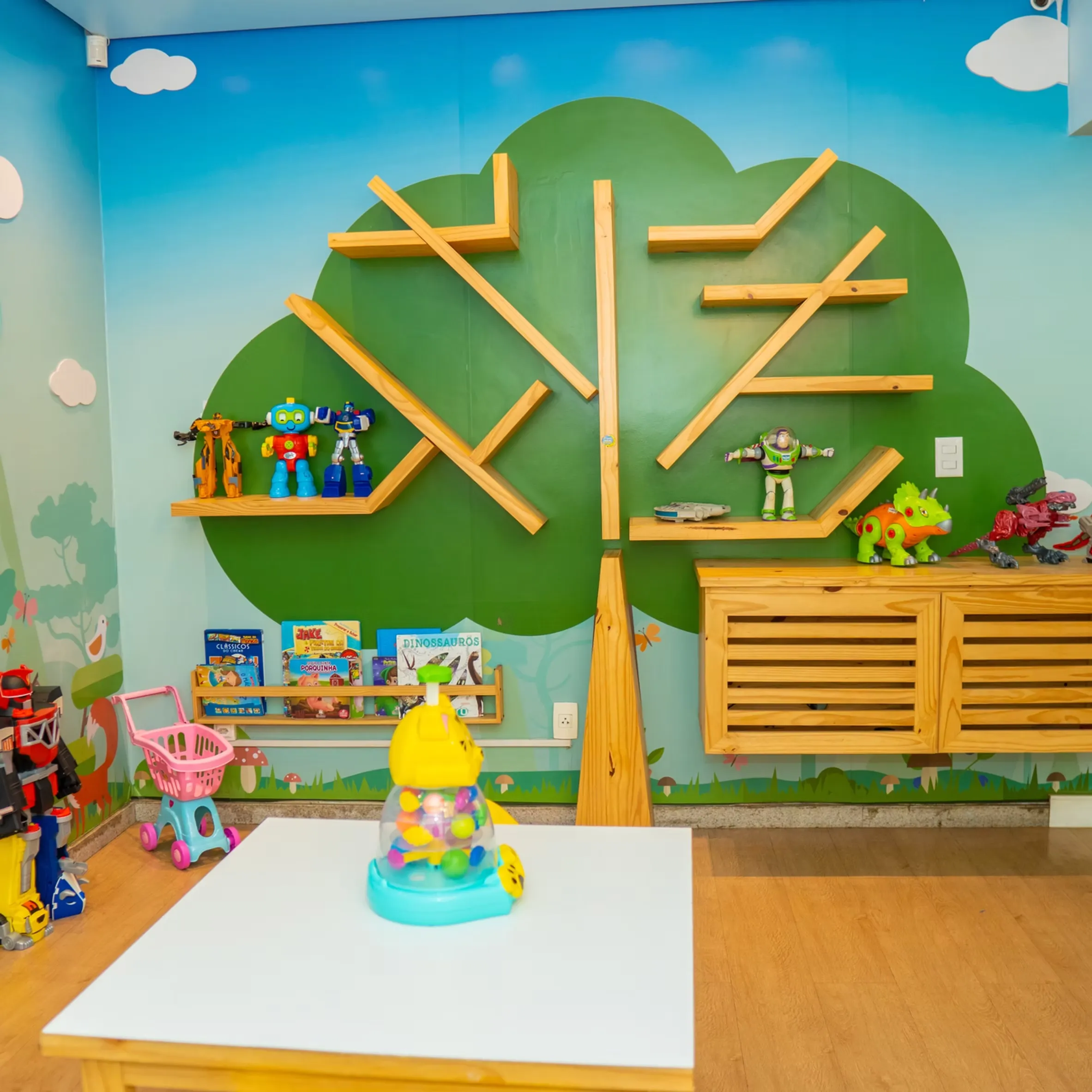Brinquedoteca da Vacinar com parede ilustrada de árvore e brinquedos