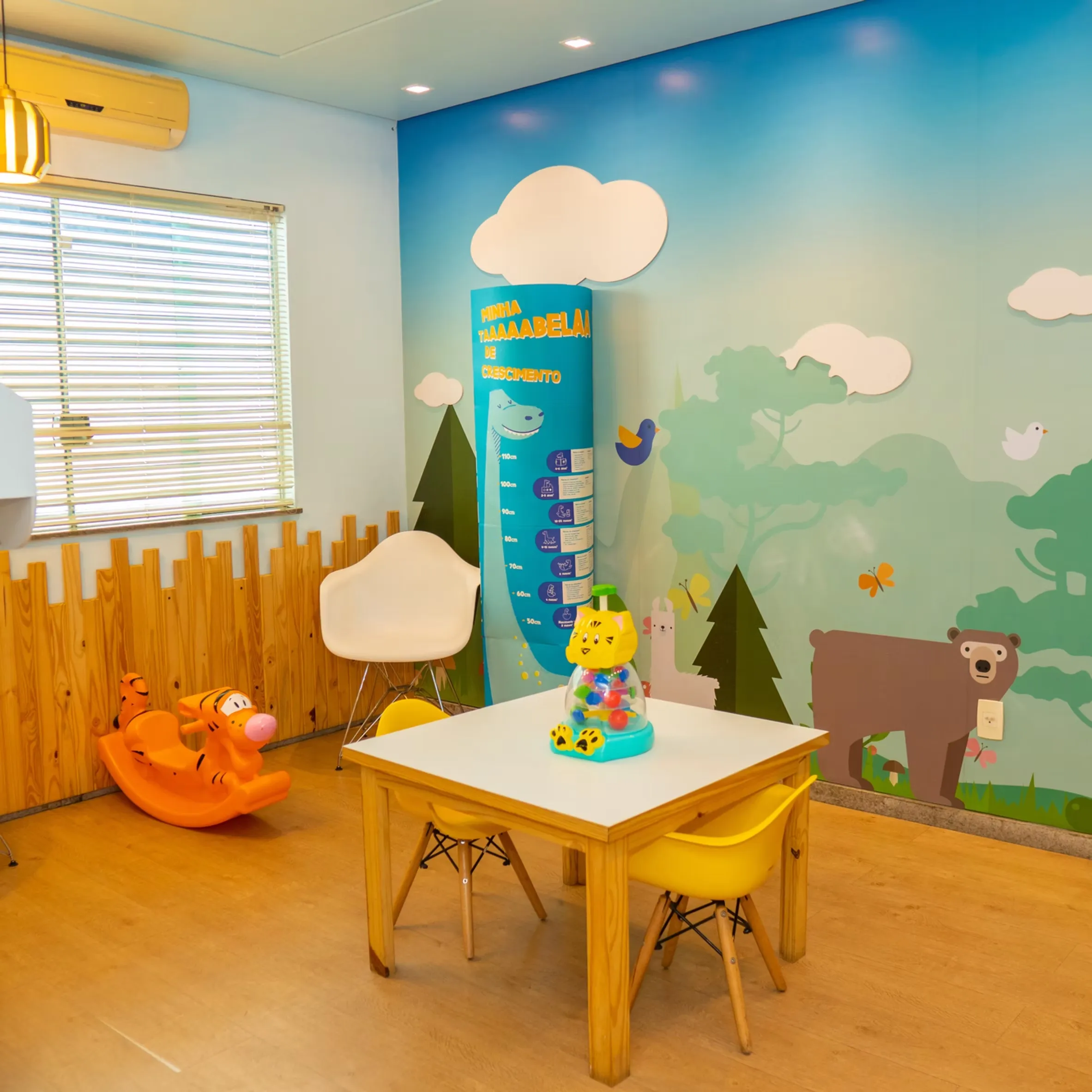 Mesinha infantil e régua de crescimento na brinquedoteca da Vacinar