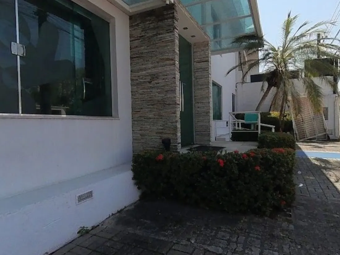 Entrada da clínica Vacinar, com jardim e revestimento de pedra