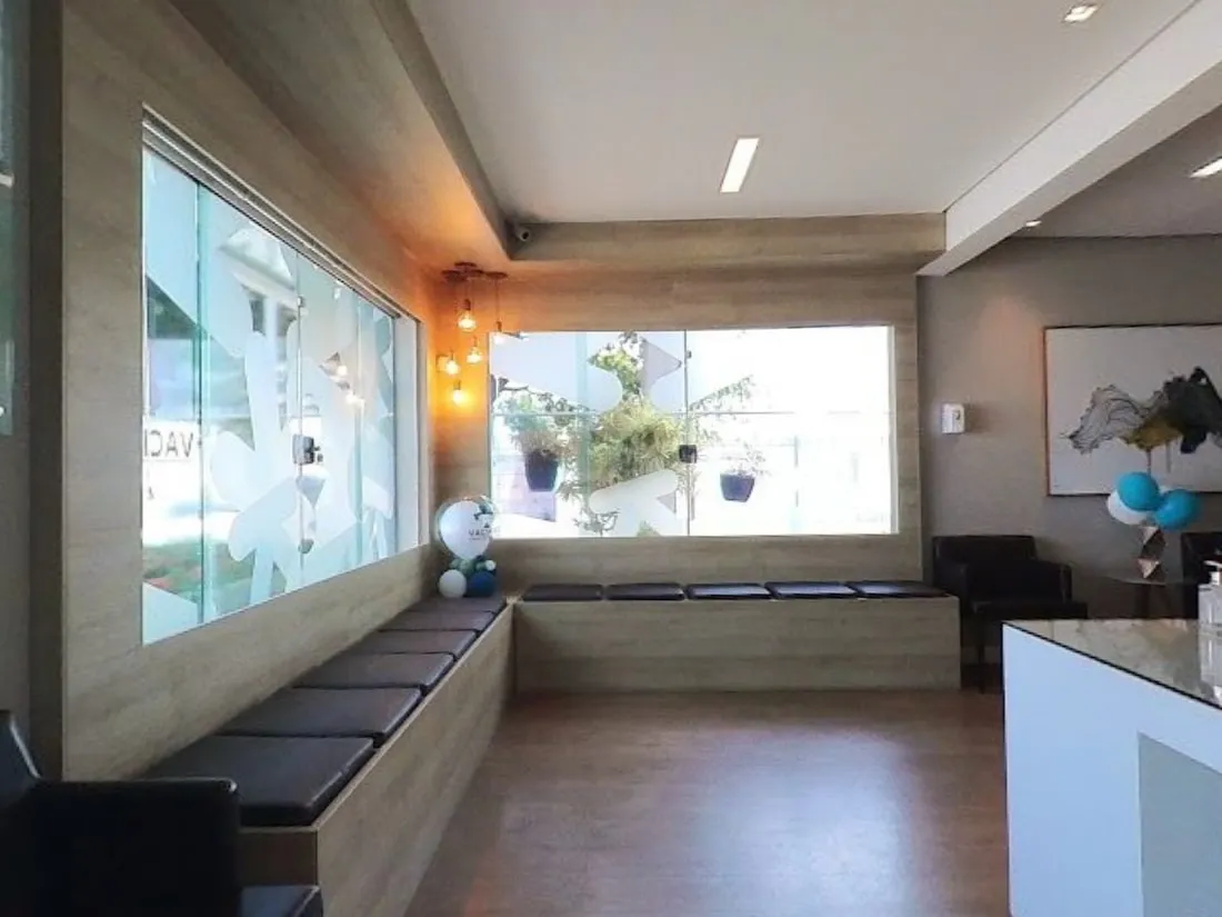 Sala de espera da Vacinar, com bancos de madeira e ambiente claro